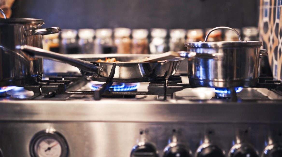 Casseroles et poêles en inox sur une cuisinière professionnelle, illustrant les avantages de l'inox en cuisine.