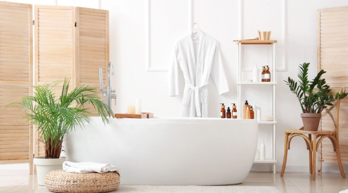 Salle de bain moderne et zen avec baignoire îlot blanche, plantes vertes, accessoires naturels et lumière douce, créant une ambiance spa apaisante.